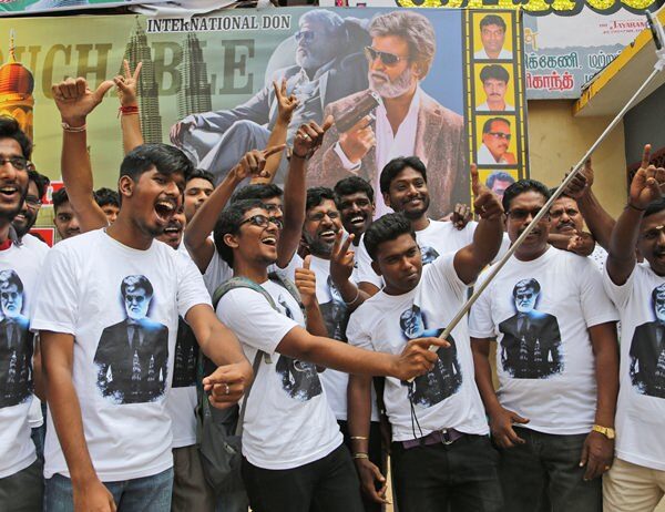 Fans take a group picture in front of the "Kabali" movie poster.