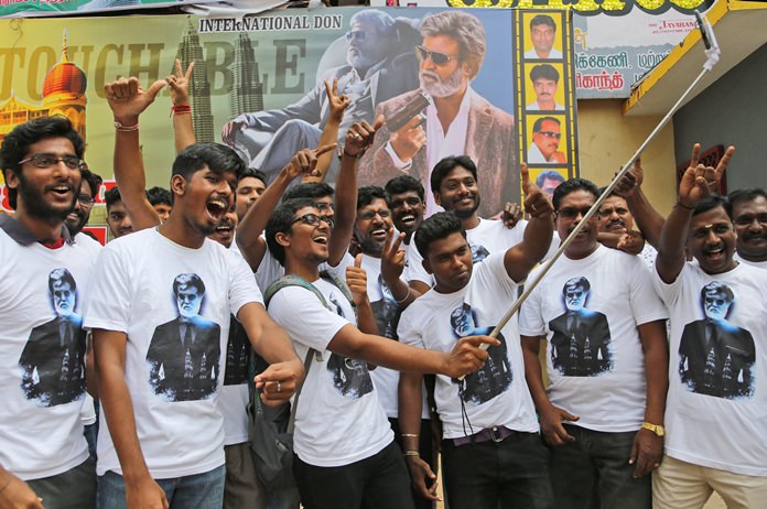 Fans take a group picture in front of the "Kabali" movie poster.