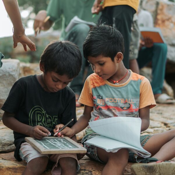 Two boys reading a book together. One helping the other.